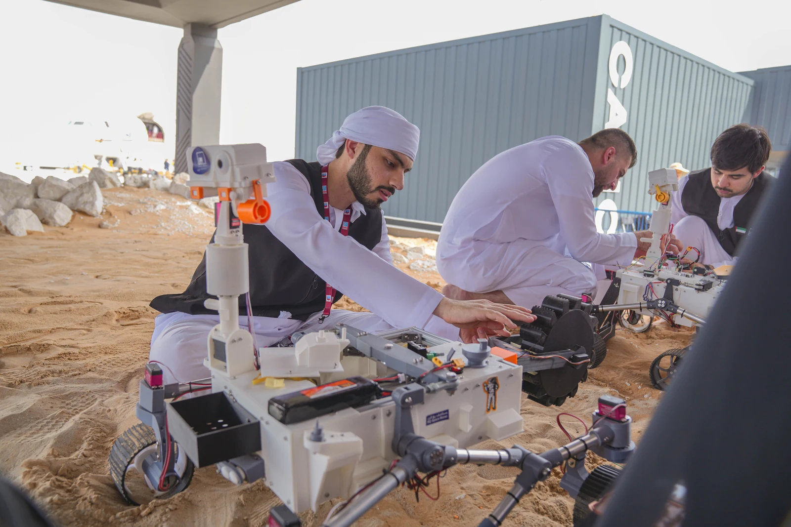 People adjusting mobile robots together at an outdoor workbench