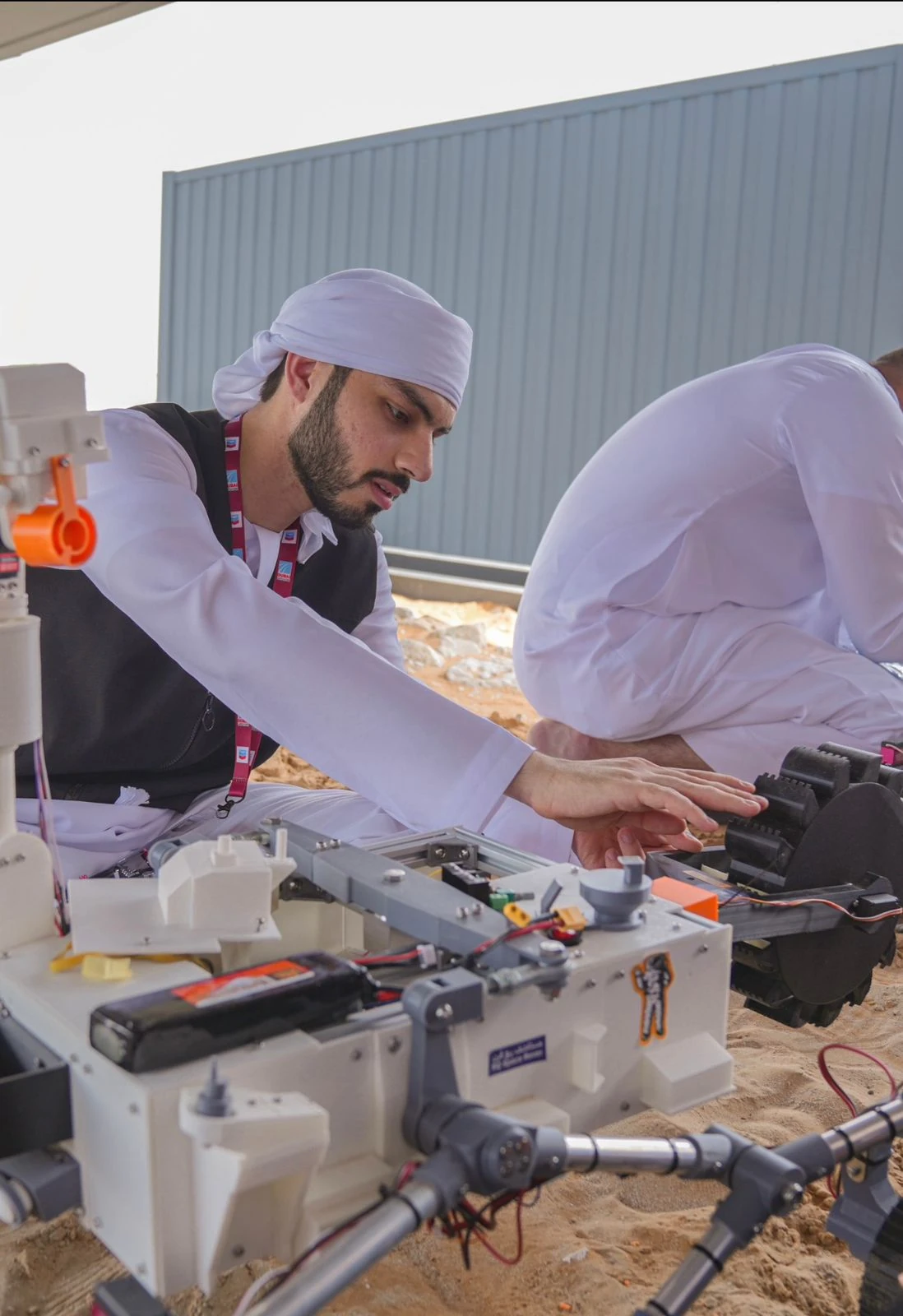 A person working on a mobile robot at an outdoor workbench